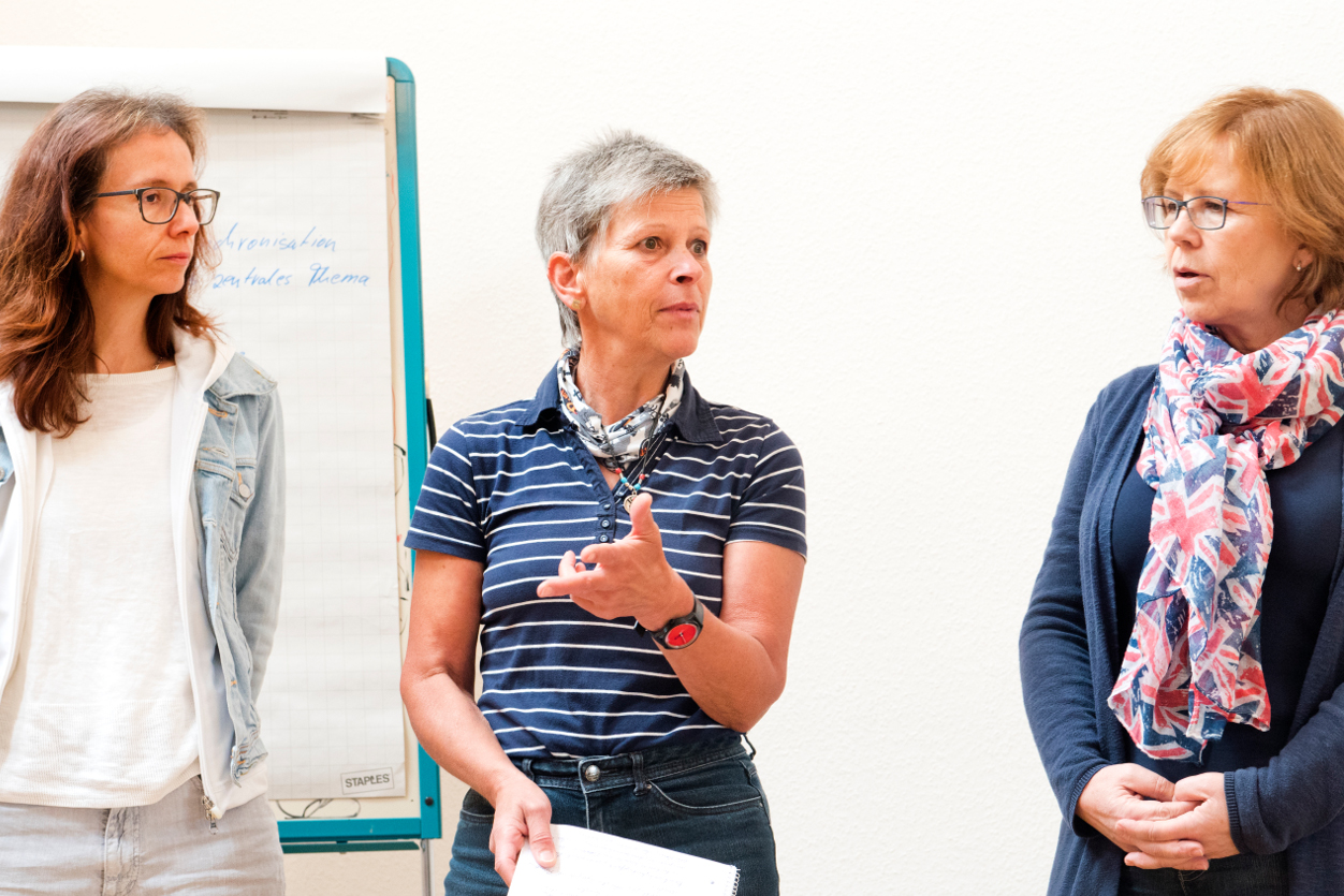 Drei Frauen diskutieren engagiert während einer Ausbildung am Adler Dreikurs Institut