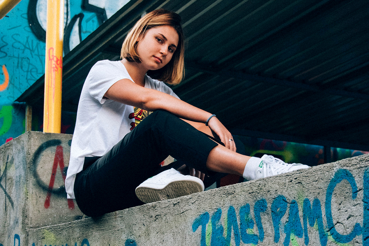 Junge Frau sitzt auf einer mit Graffiti besprayten Mauer © Unsplash / Daniil Kuželev