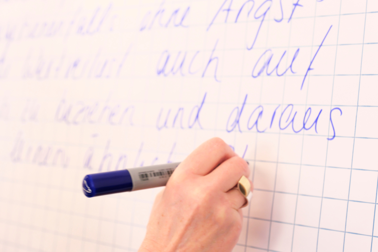 Es ist nicht leicht, eine ermutigende Führungskultur aufzubauen, aber es ist möglich Frau schreibt an Wandtafel mit dickem blauem Filzstift