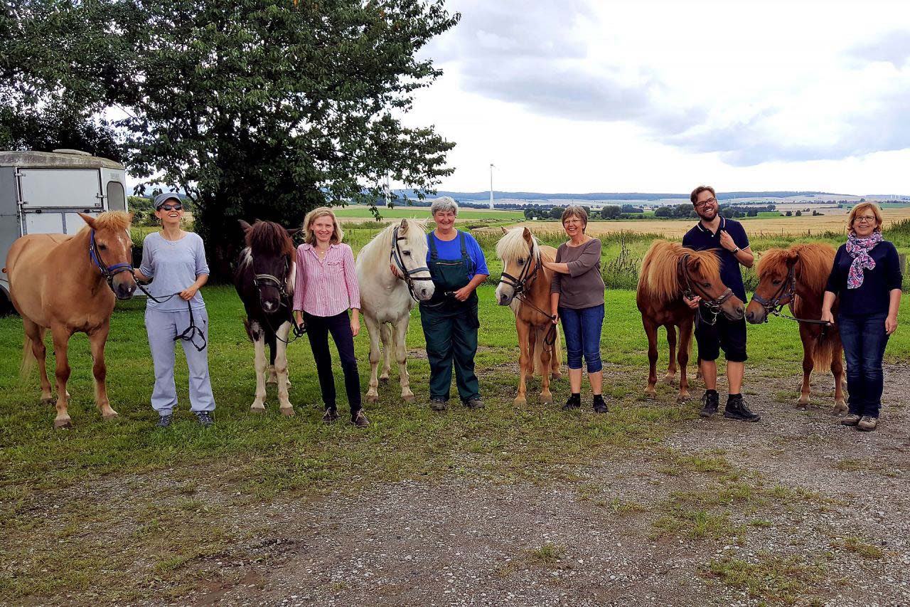 Teilnehmende des Seminars «Pferde stärken» stehen zusammen mit den vierbeinigen Lehrmeistern im Halbkreis