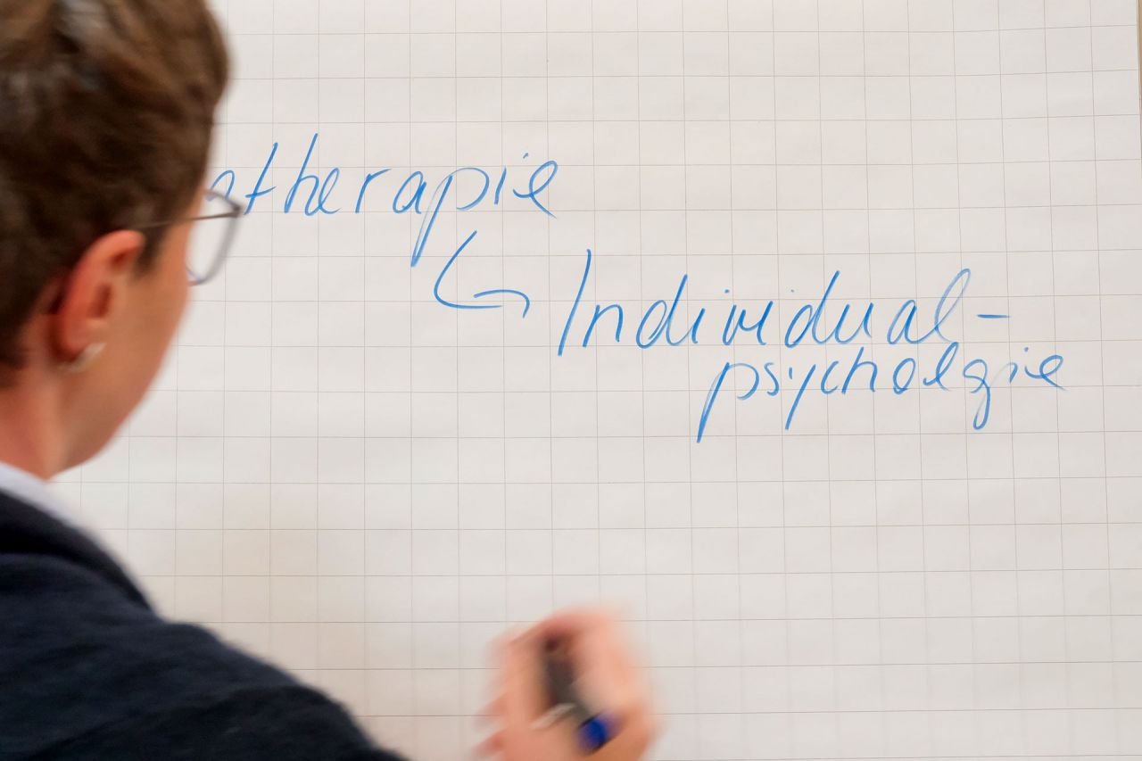 Individualpsychologisches Intensivseminar Frau schreibt Individualpsychologie an eine Wandtafel