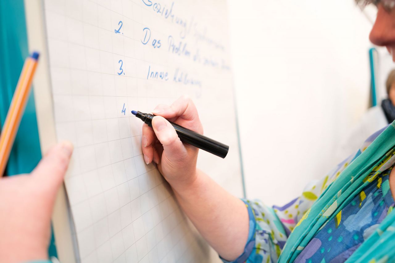 Eine Frau schreibt auf eine grosse Papiertafel
